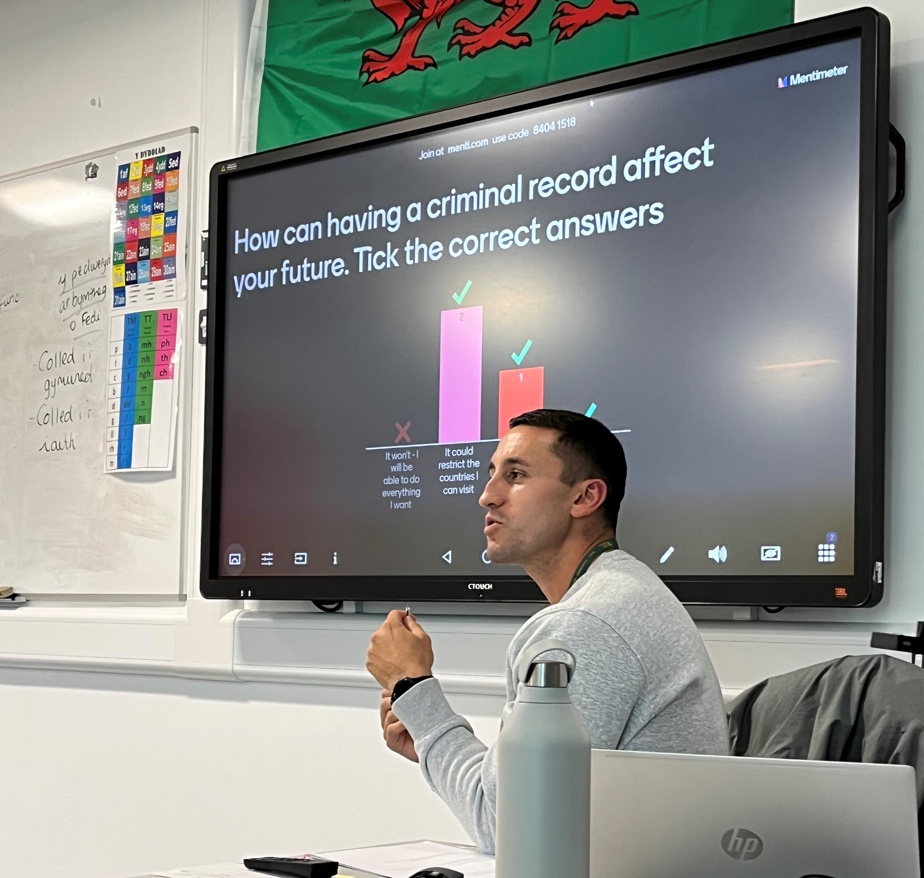 Youth offending service worker in front TV screen showing the question: How can having a criminal record affect your future? 