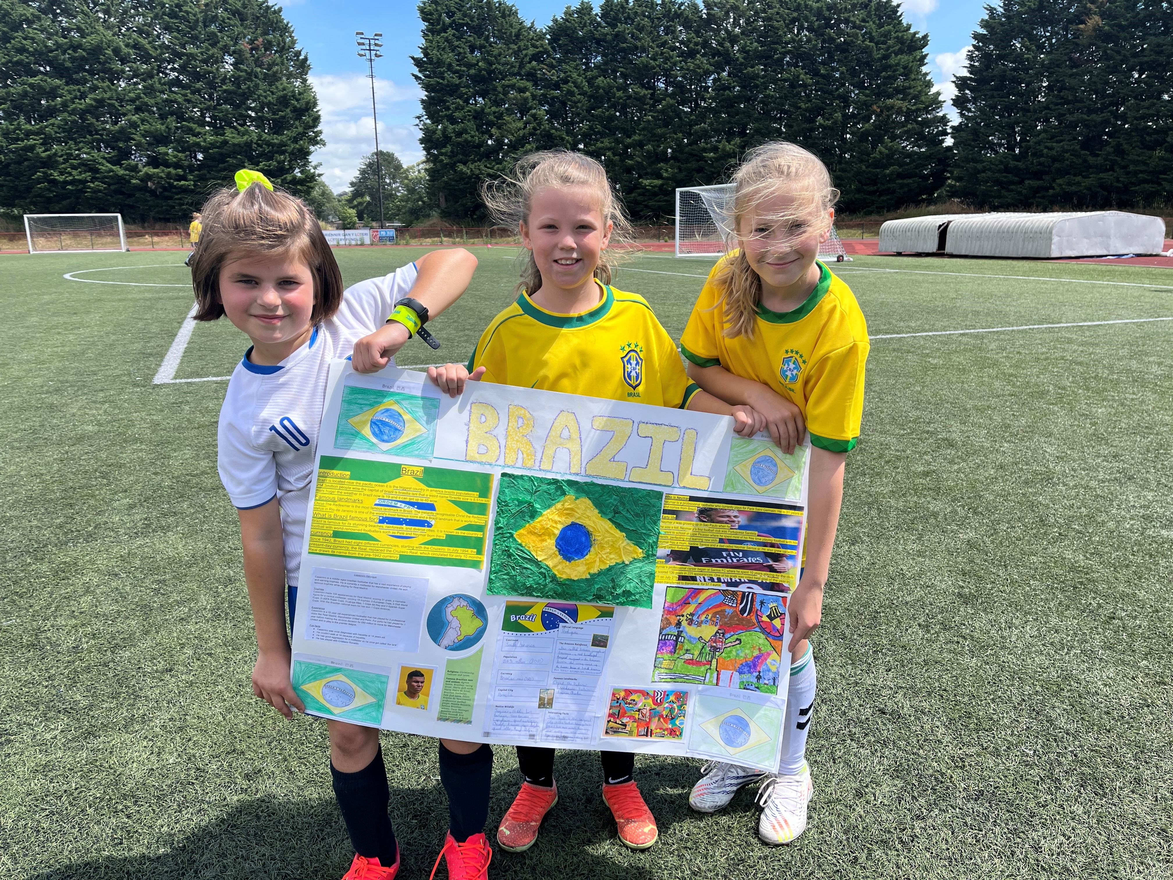 Three pupils from Torfaen holding a poster depicting information about Brazil 