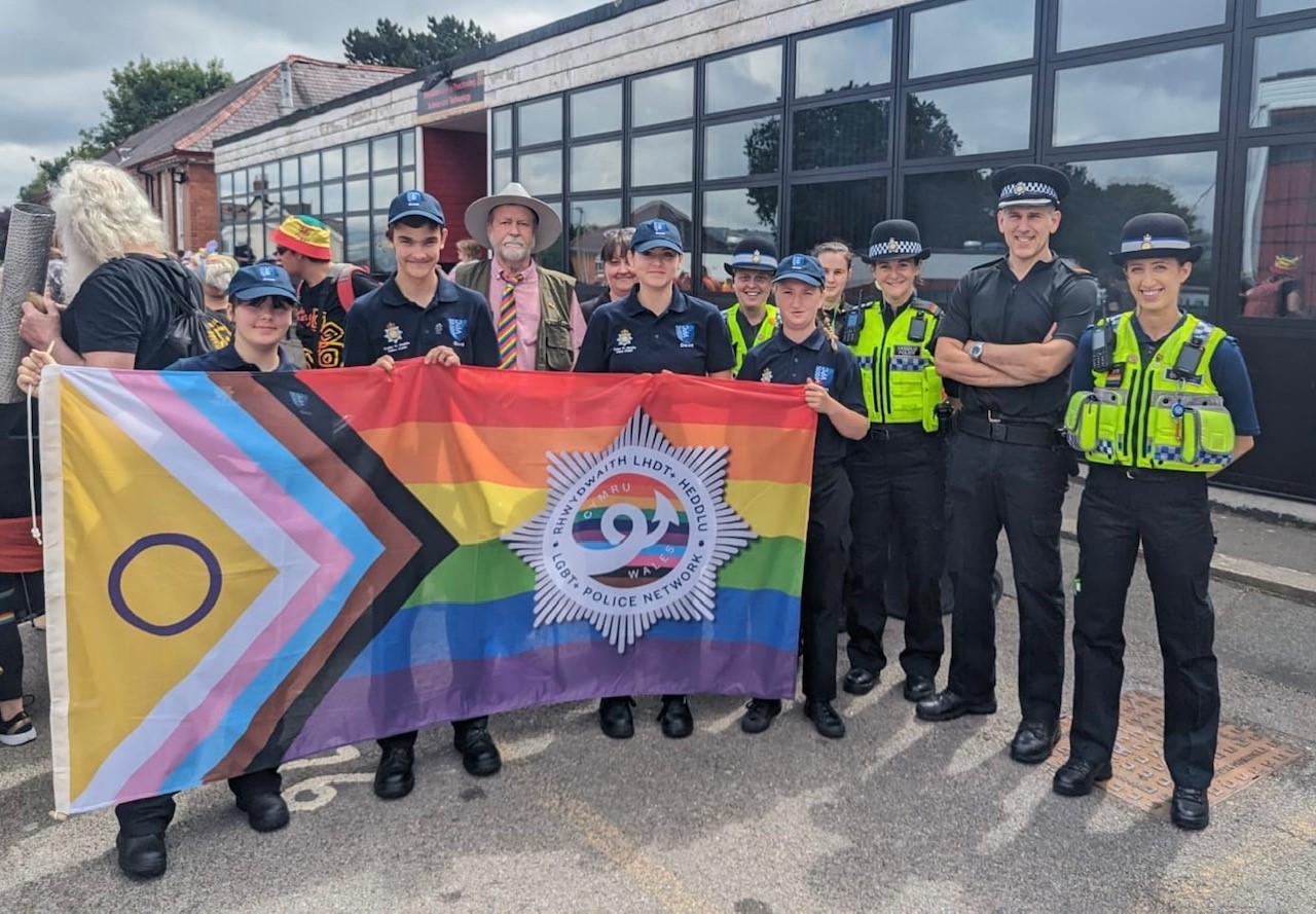 Jeff Cuthbert standing with officers and cadets in front of Pride flag 