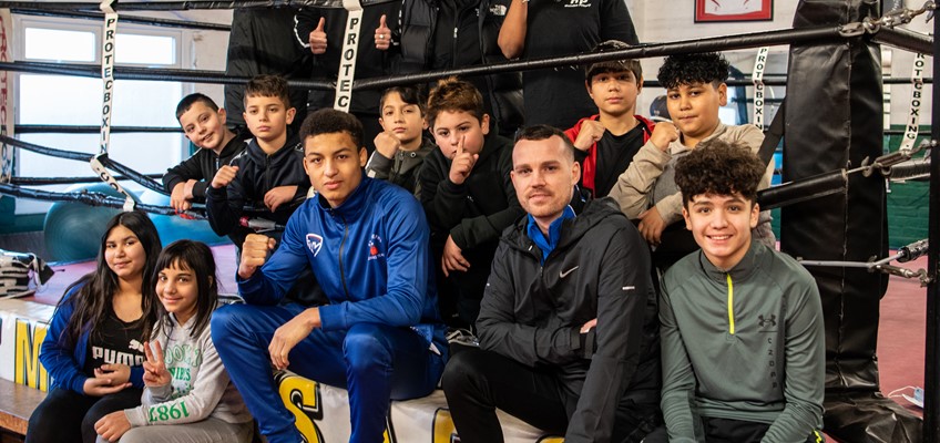 Group of children and staff sitting on edge of boxing ring