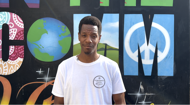community youth project staff member stood against graffiti backdrop