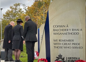 Commissioner, Chief Constable and Pastor with heads bowed towards memorial stone