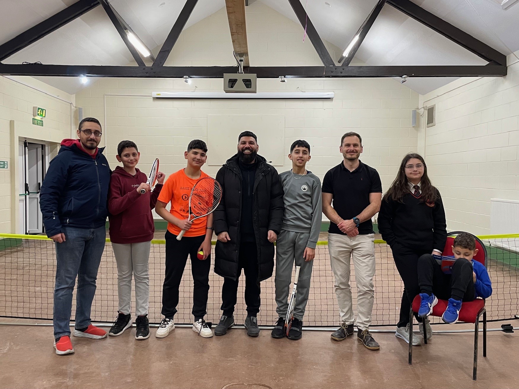 Members of youth club standing in front of tennis net