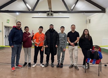 Members of youth club standing in front of tennis net