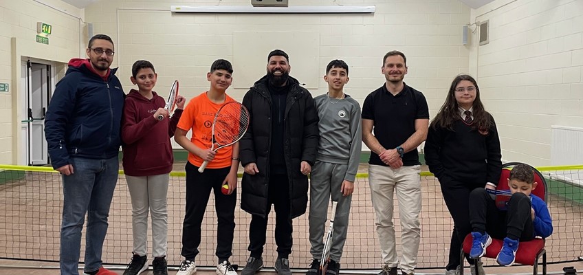 Members of youth club standing in front of tennis net